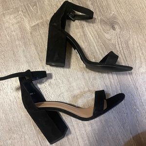 Black faux suede heeled block sandals with ankle buckle closure.